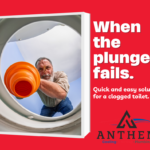 A man in overalls and gloves using a plunger to unclog a toilet in a clean bathroom.