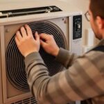 HVAC technician performing a spring air conditioner tune-up, focusing on cleaning filters and inspecting coils for optimal system performance.